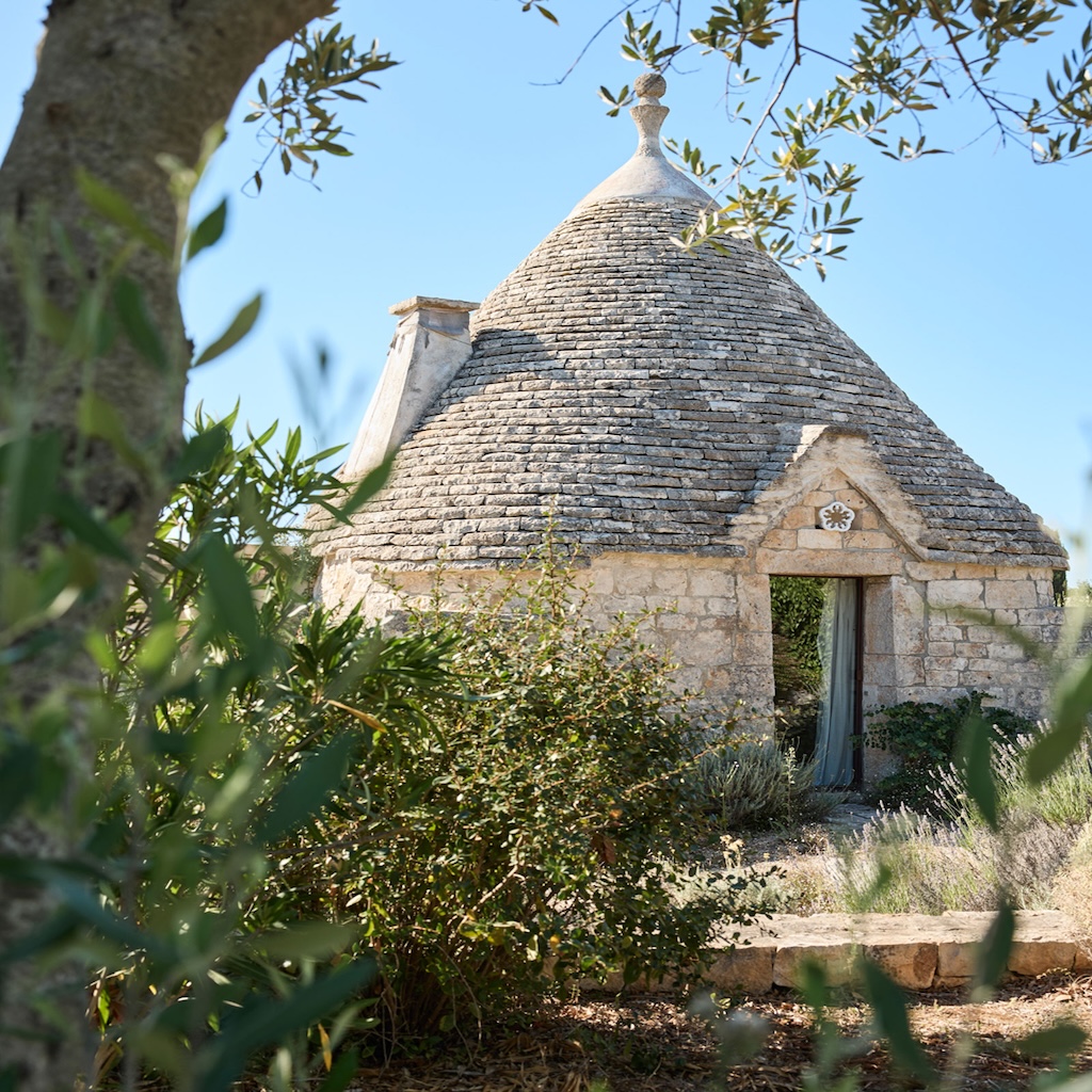 Vue extérieure d’un trullo traditionnel dans les Pouilles, avec toits coniques en pierre sèche.